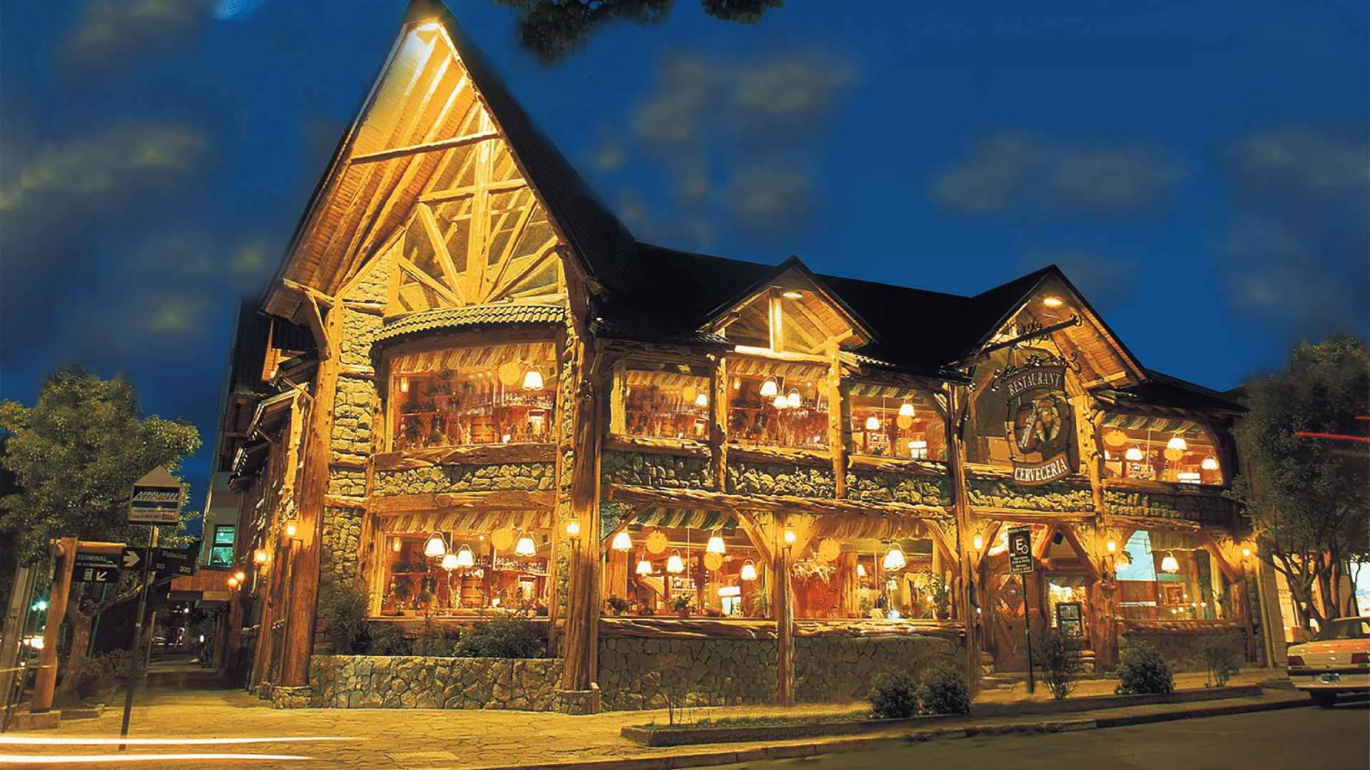 Fachada de madera del restaurante Familia Weiss iluminada de noche